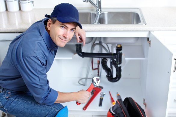 Mature plumber fixing a sink at kitchen