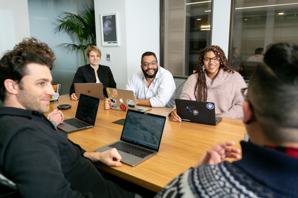 Team members in a meeting using their computers to understand service knowledge software and its importance in modern business